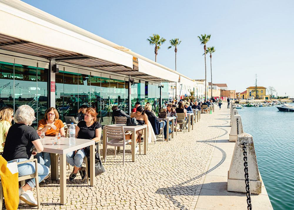 Outdoor waterfront restaurant with people dining.