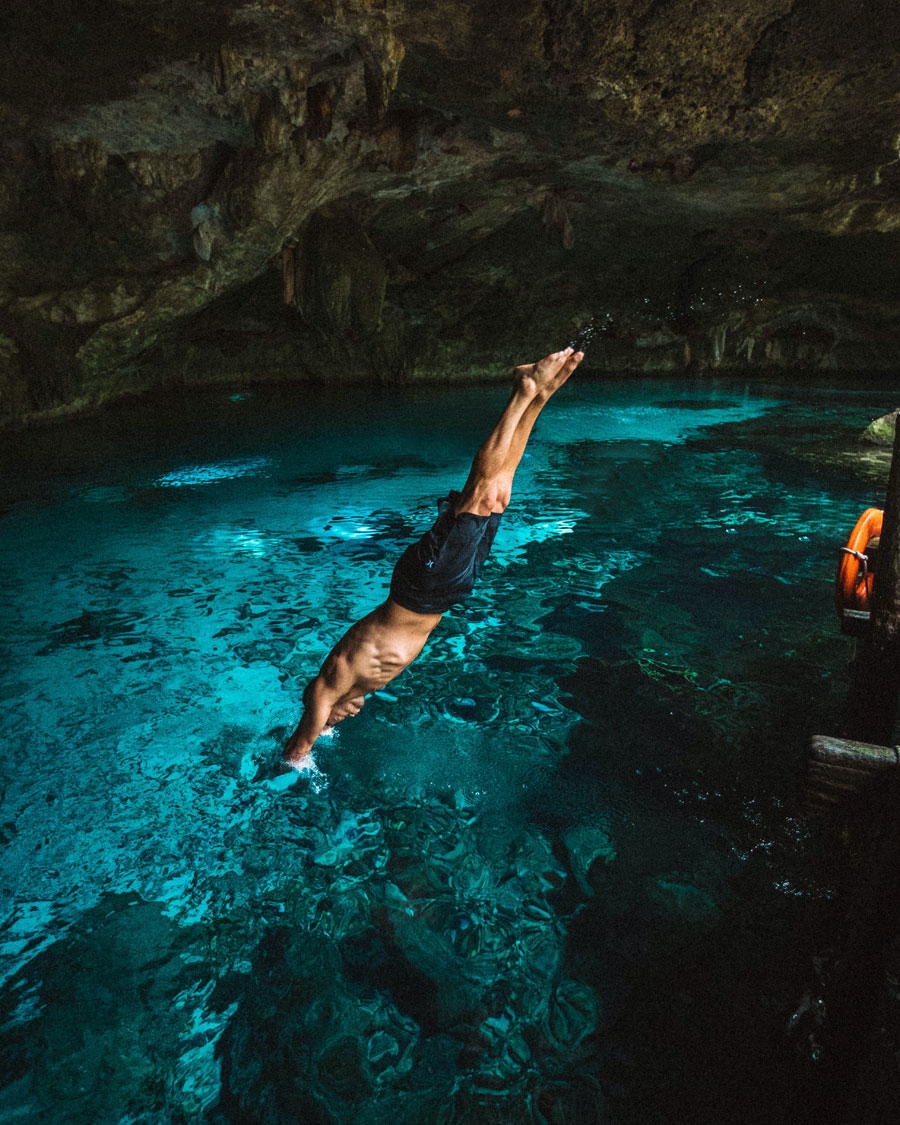 Person diving into cave pool.