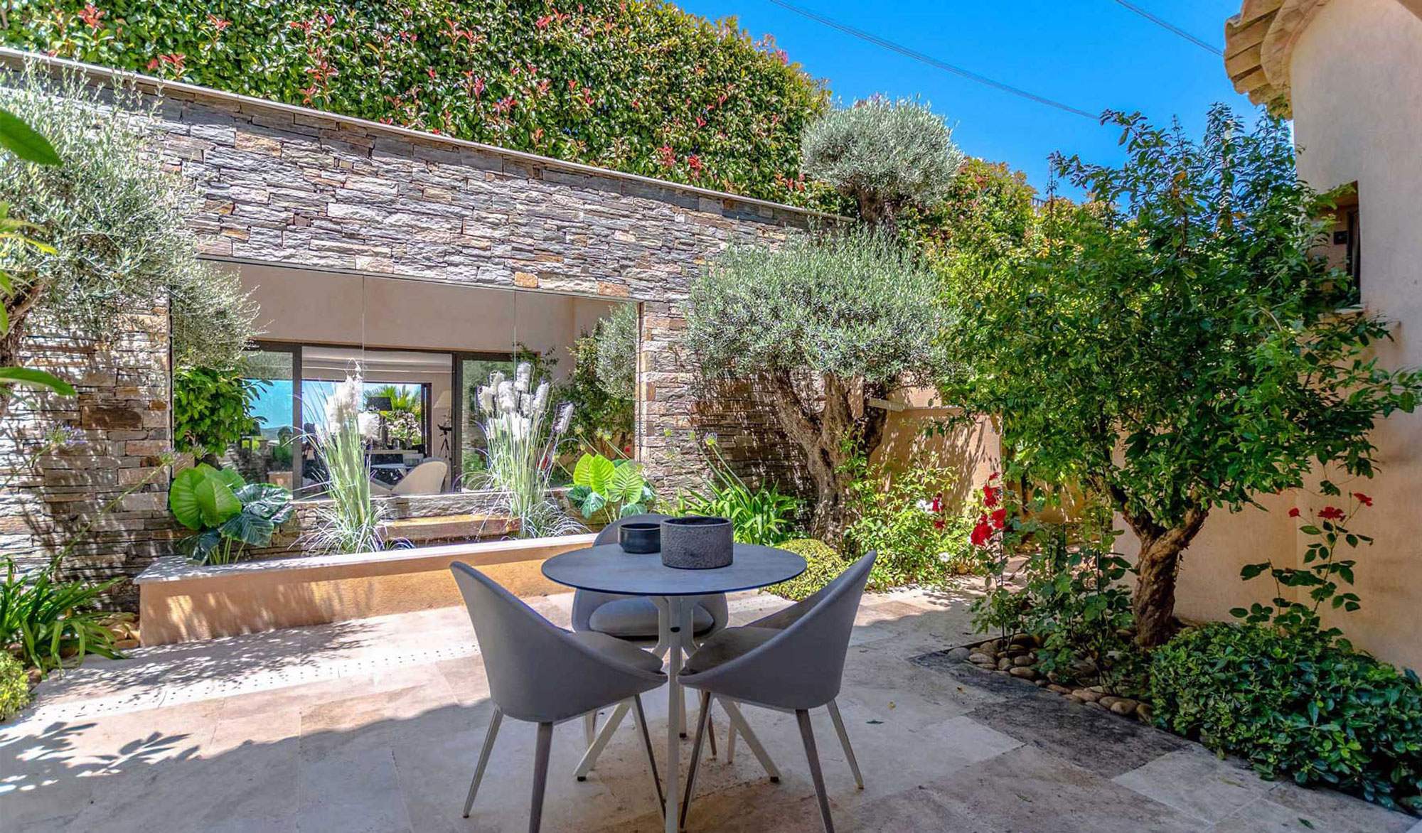 Outdoor patio with table and chairs, lush garden.