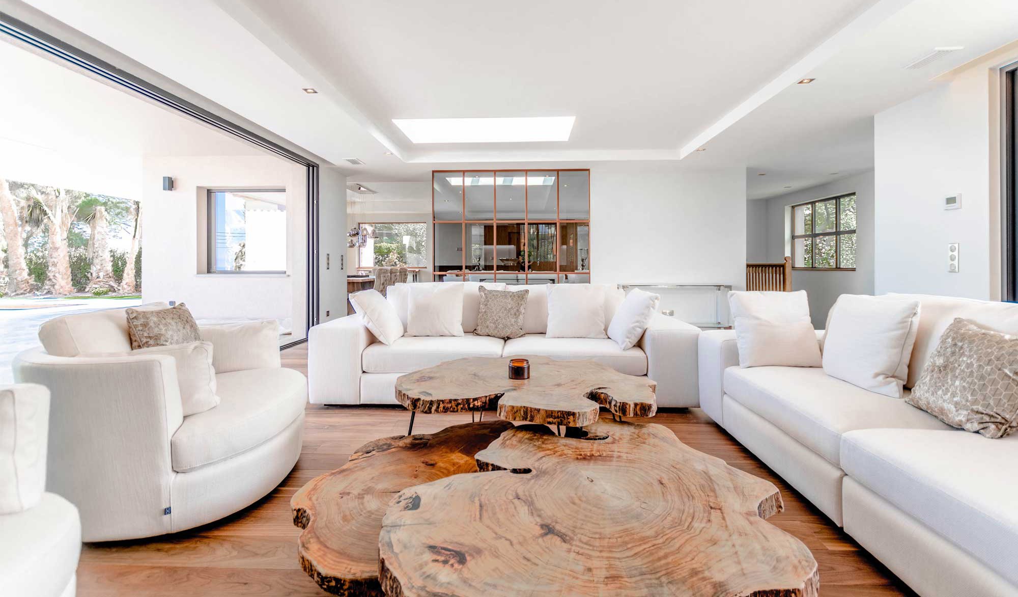 Spacious living room with white sofas and wood table.